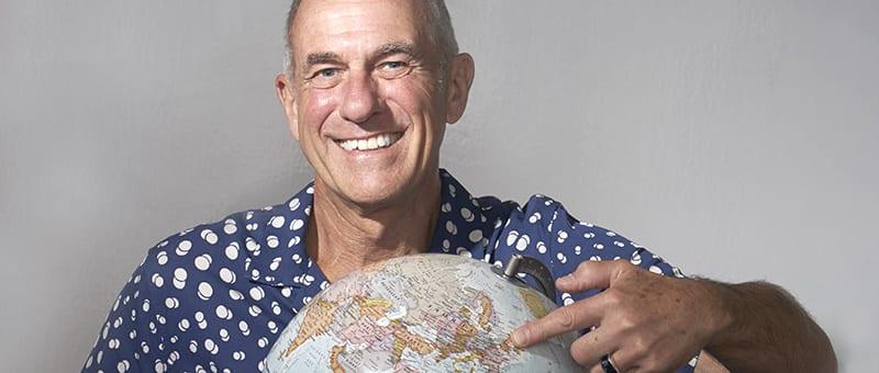 Professor Kevin Stokes pointing at a globe